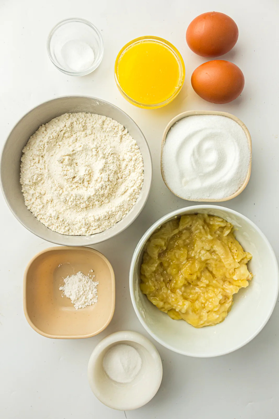 Ingredients for bread machine banana bread: mashed banana, eggs, melted butter, sugar, bread flour, baking soda and salt