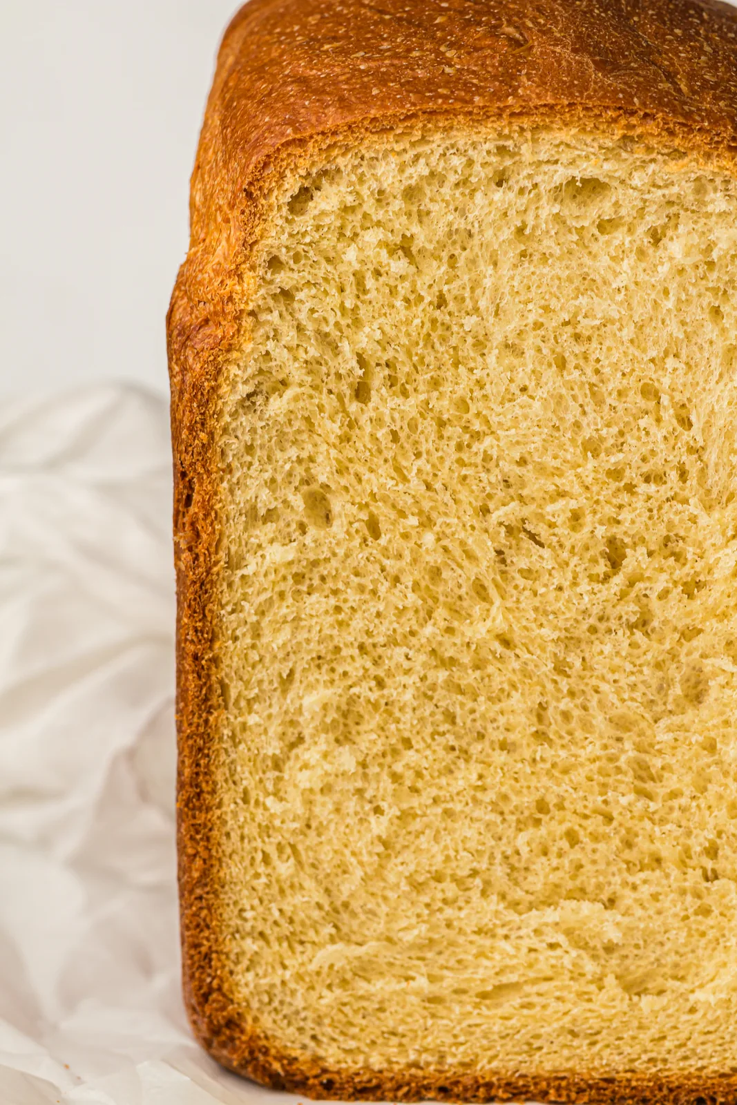 A tall, buttery yellow loaf with a feathery crumb, cut open to show the soft inside