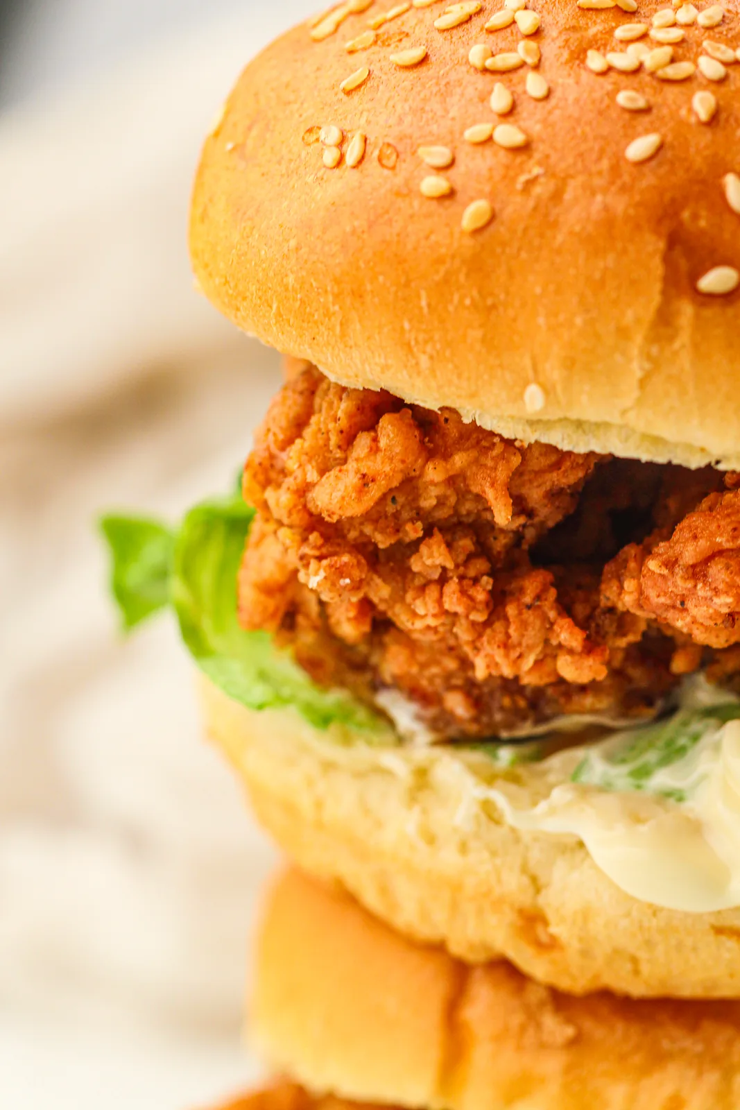 Close up of a tall sesame bun packed with golden fried fillet and shredded lettuce