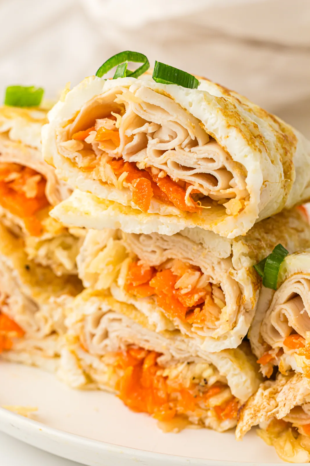Rolled and halved parcels stacked on a plate showing turkey and shredded carrot inside