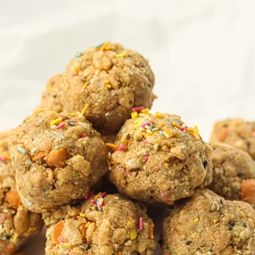 A pile of no-bake energy balls with sprinkles on parchment paper