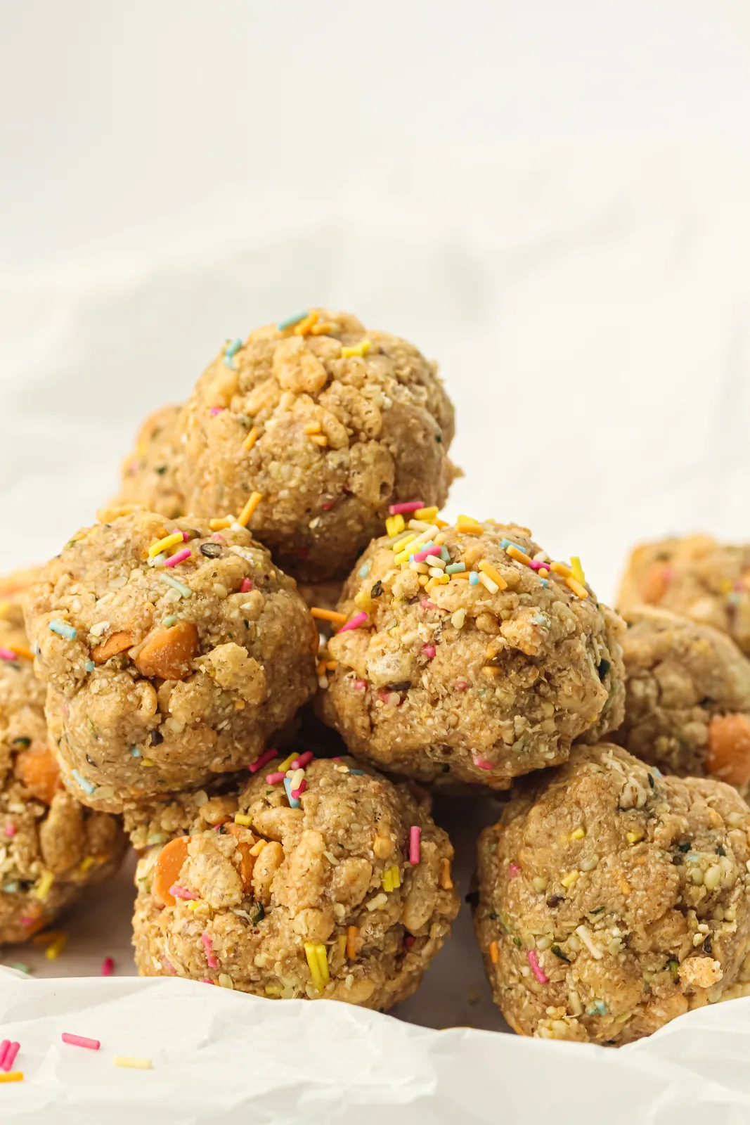 A pile of no-bake energy balls with sprinkles on parchment paper
