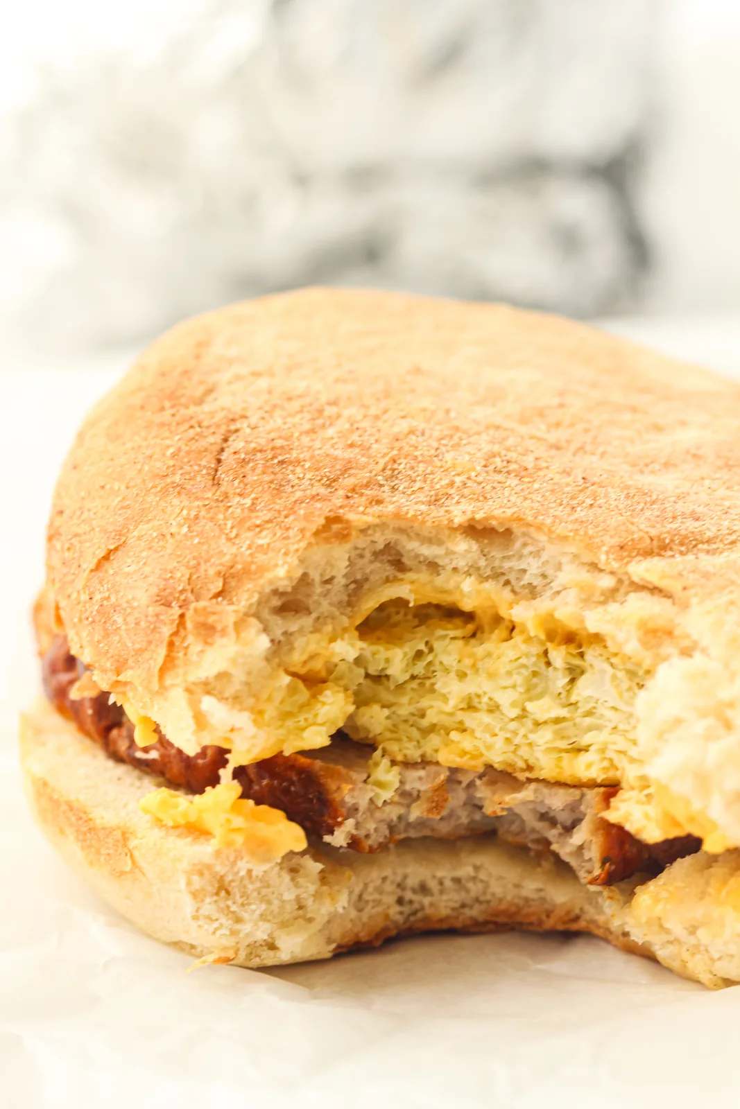 Cross section of a muffin sandwich showing a thick layer of baked egg and melted cheese