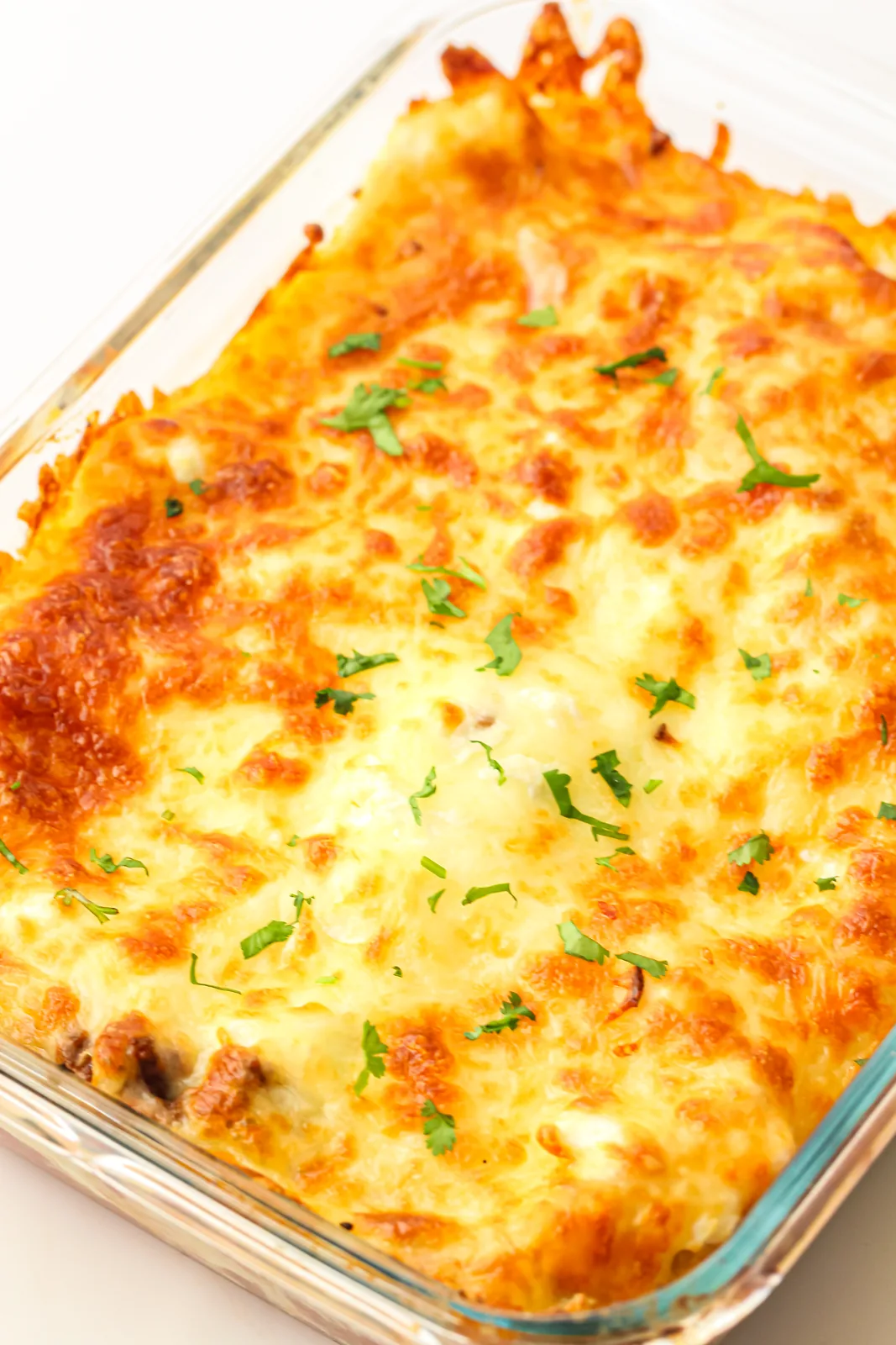 Golden bubbling lasagne baked in a glass dish and scattered with parsley