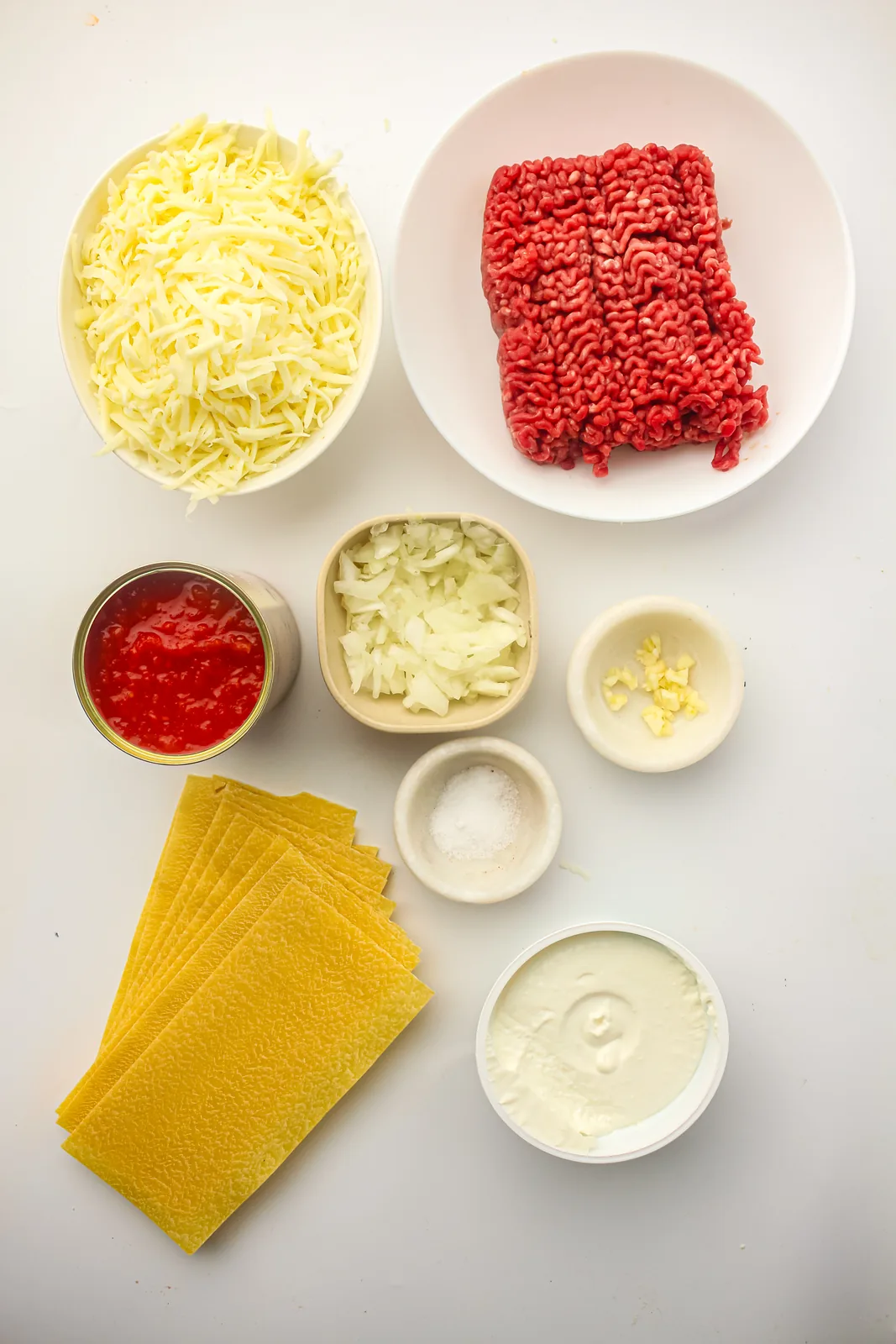 Ingredients for freezer lasagna: pasta sheets, beef mince, tomato sauce, onion, garlic, mozzarella and ricotta
