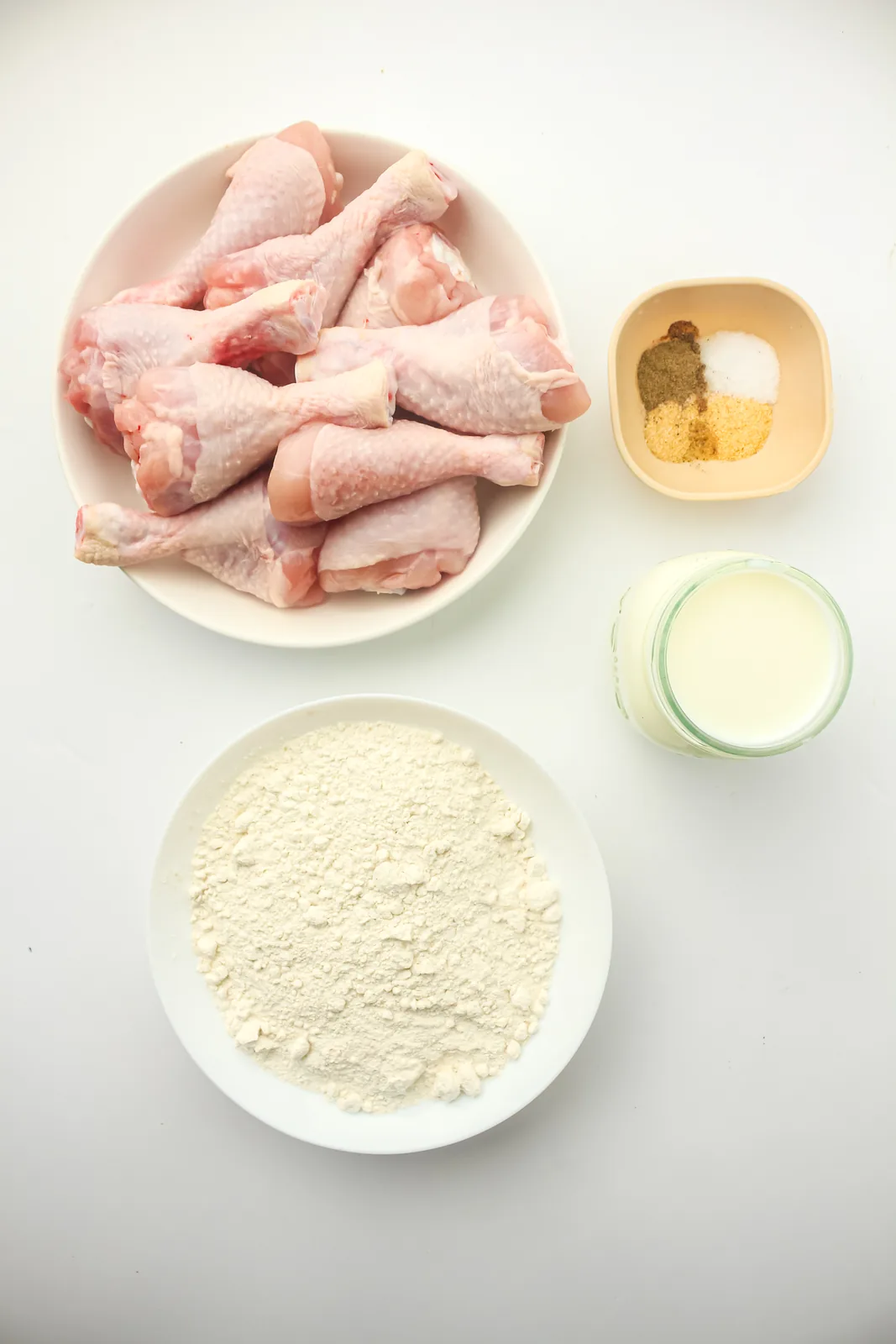 Ingredients for fried chicken drumsticks: raw legs, milk, seasoned flour, garlic and onion powder