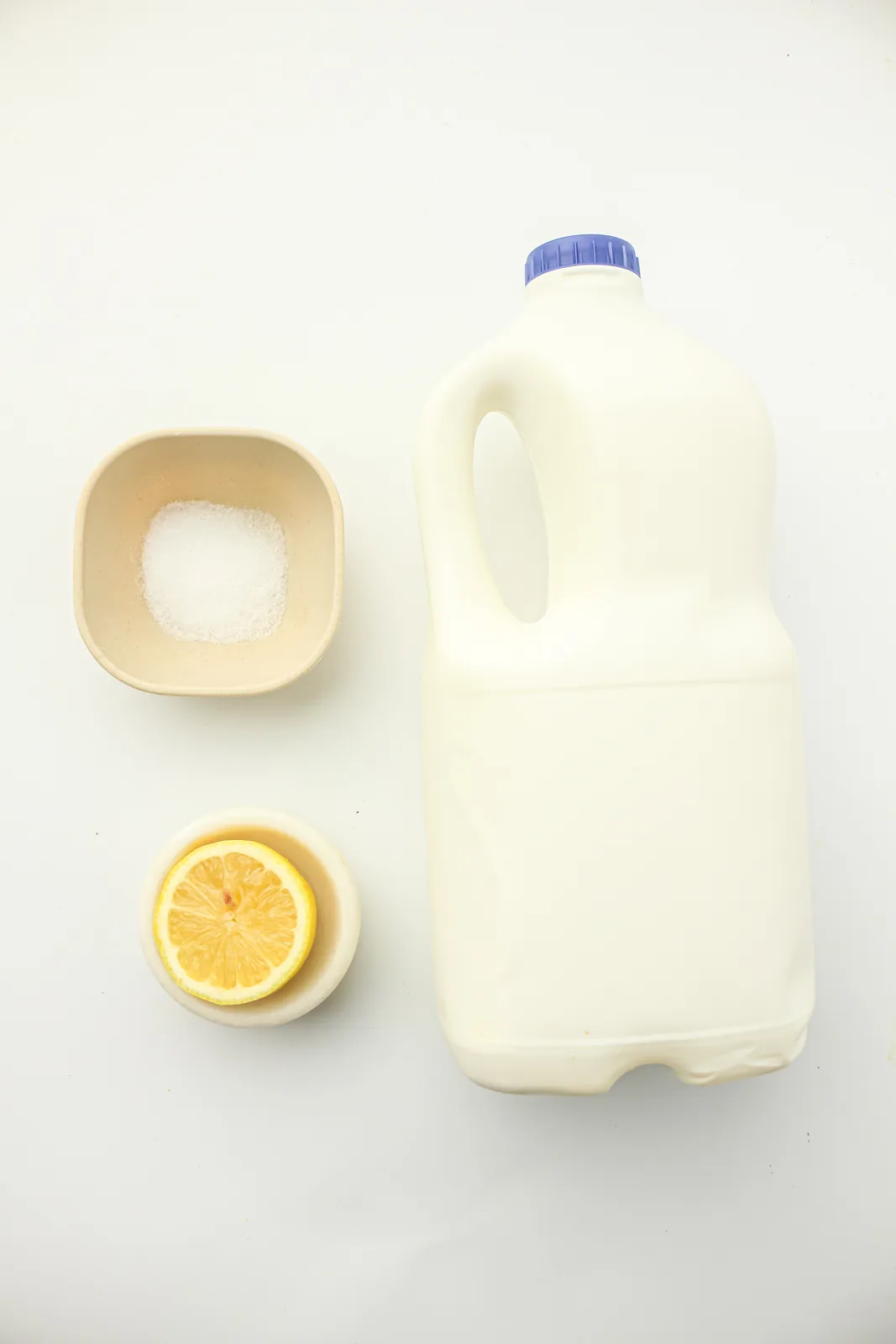 Ingredients for homemade cream cheese: a jug of whole milk, half a lemon and a small dish of salt