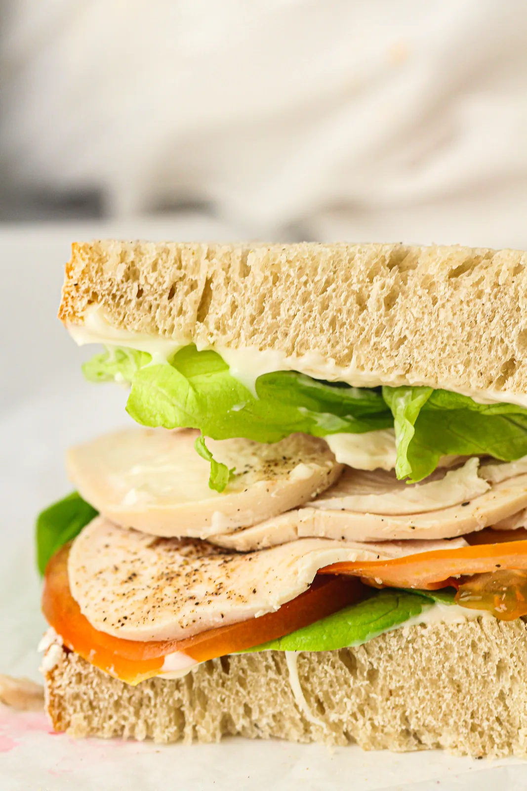 A sandwich built with thin chicken slices, lettuce and tomato