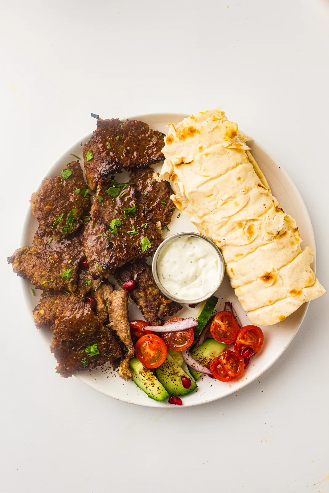 Homemade doner kebab on a plate with flatbread, garlic yogurt sauce, tomatoes and cucumber