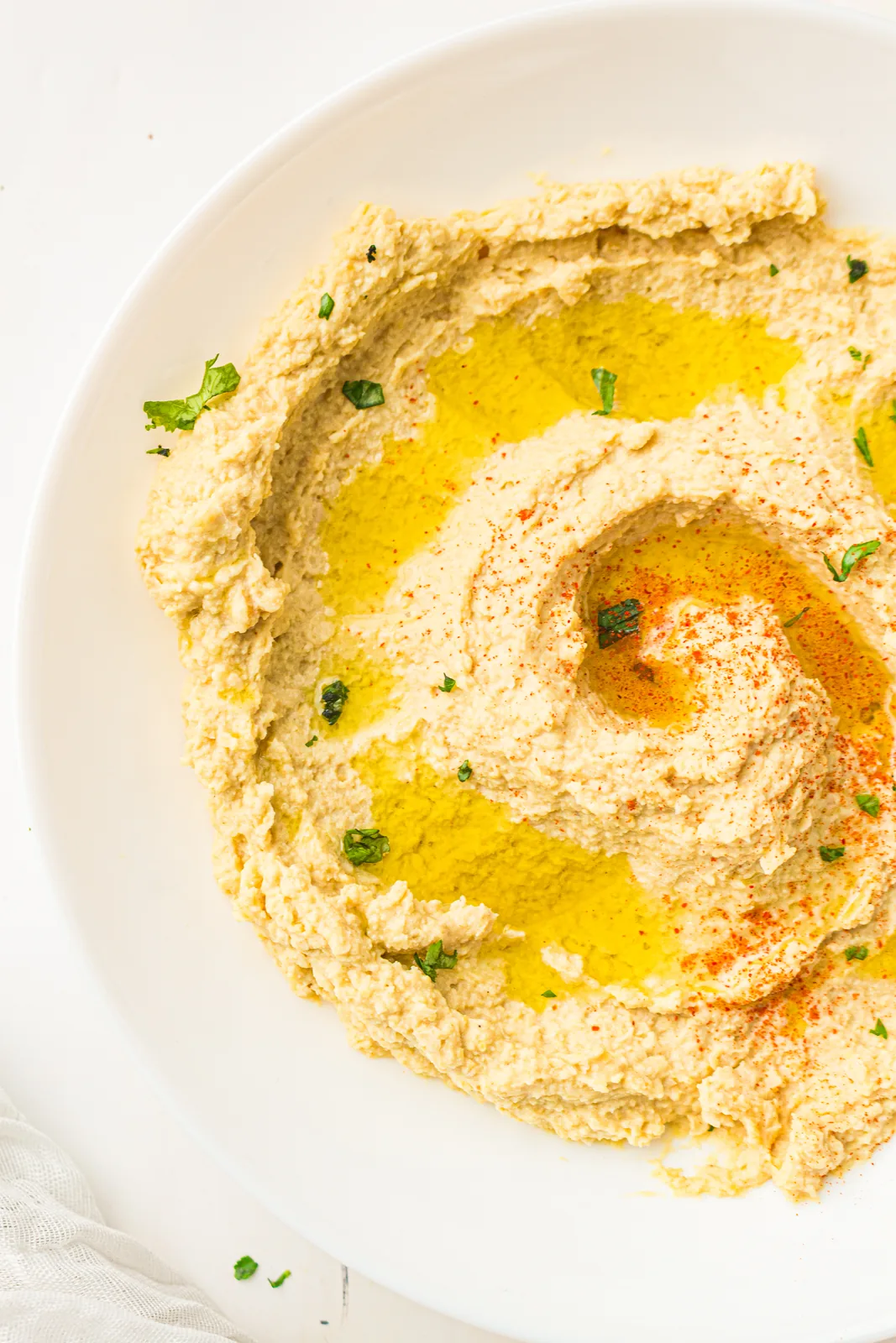 Creamy hummus swirled in a white bowl with olive oil and paprika