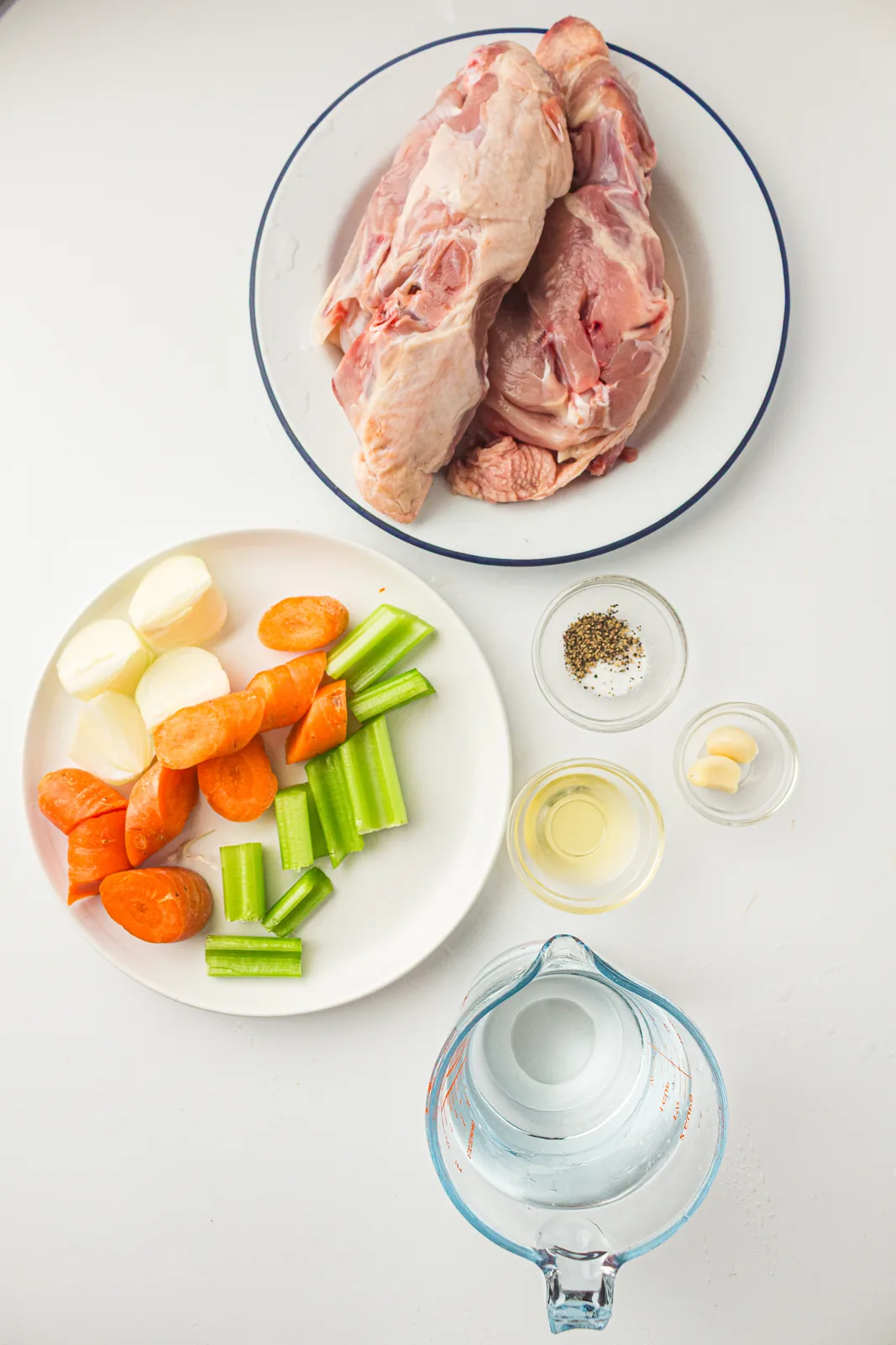 Ingredients for instant pot chicken stock: raw chicken bones, carrot, celery, onion, garlic and water
