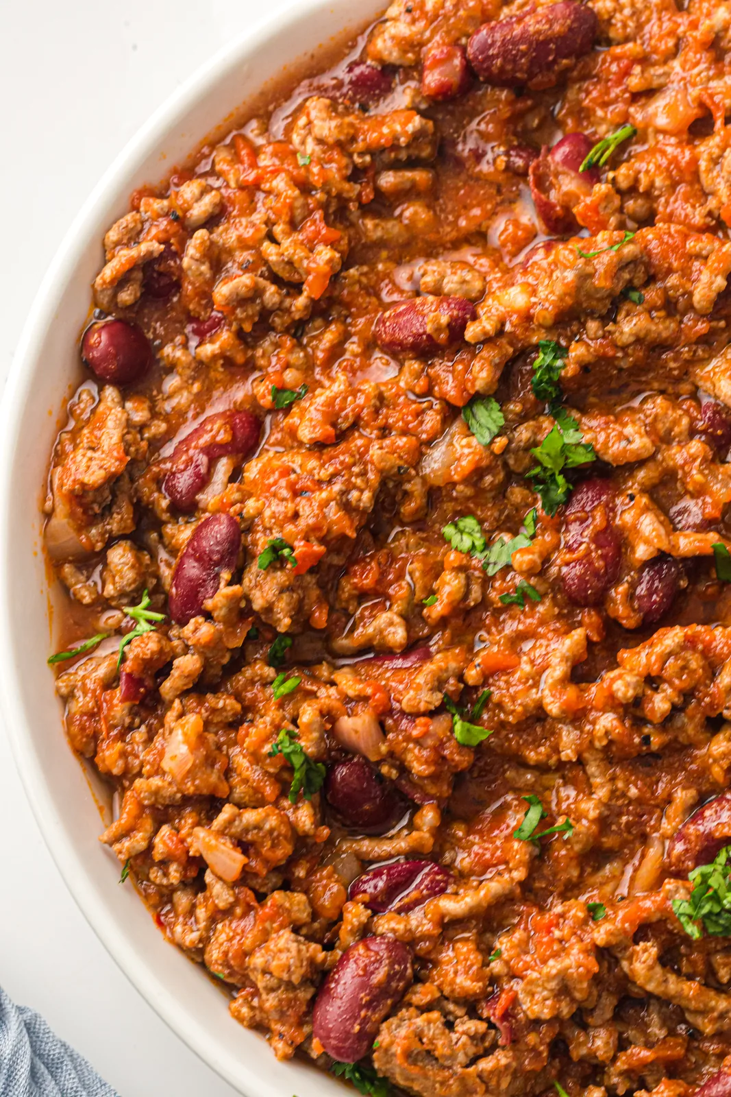 A wide dish of rich tomato and bean mince seen from above with fresh coriander