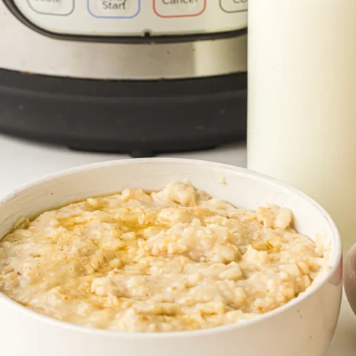 Instant pot oatmeal in a white bowl in front of the pressure cooker