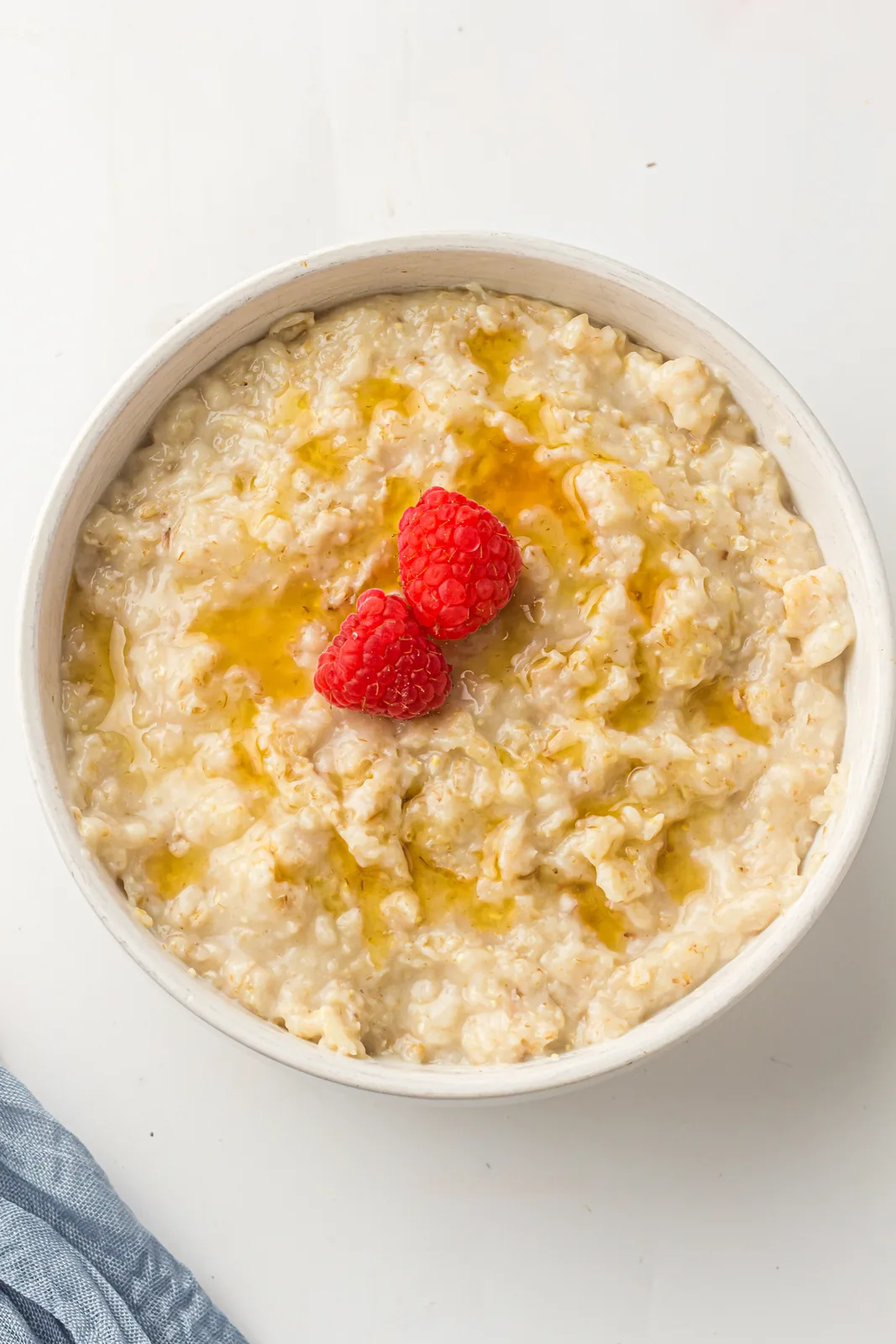 A creamy breakfast bowl topped with raspberries and a drizzle of honey