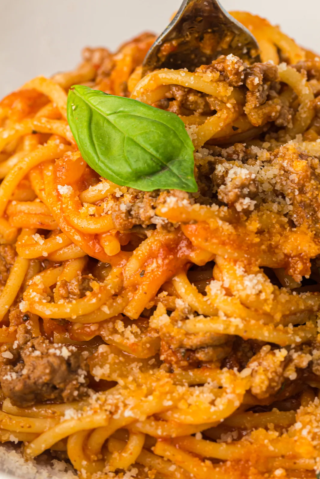 Instant pot spaghetti twirled on a plate with basil and grated parmesan