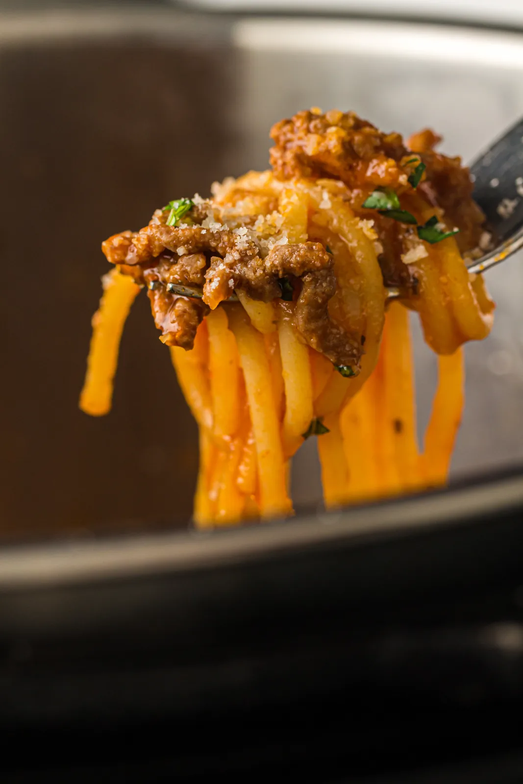 A forkful of saucy noodles lifted above the pressure cooker