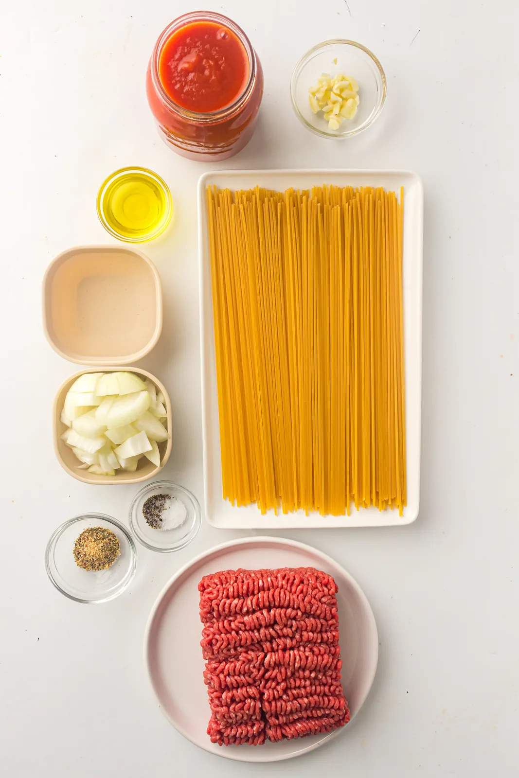 Ingredients for instant pot spaghetti: dry pasta, ground beef, jarred sauce, onion, garlic and seasonings