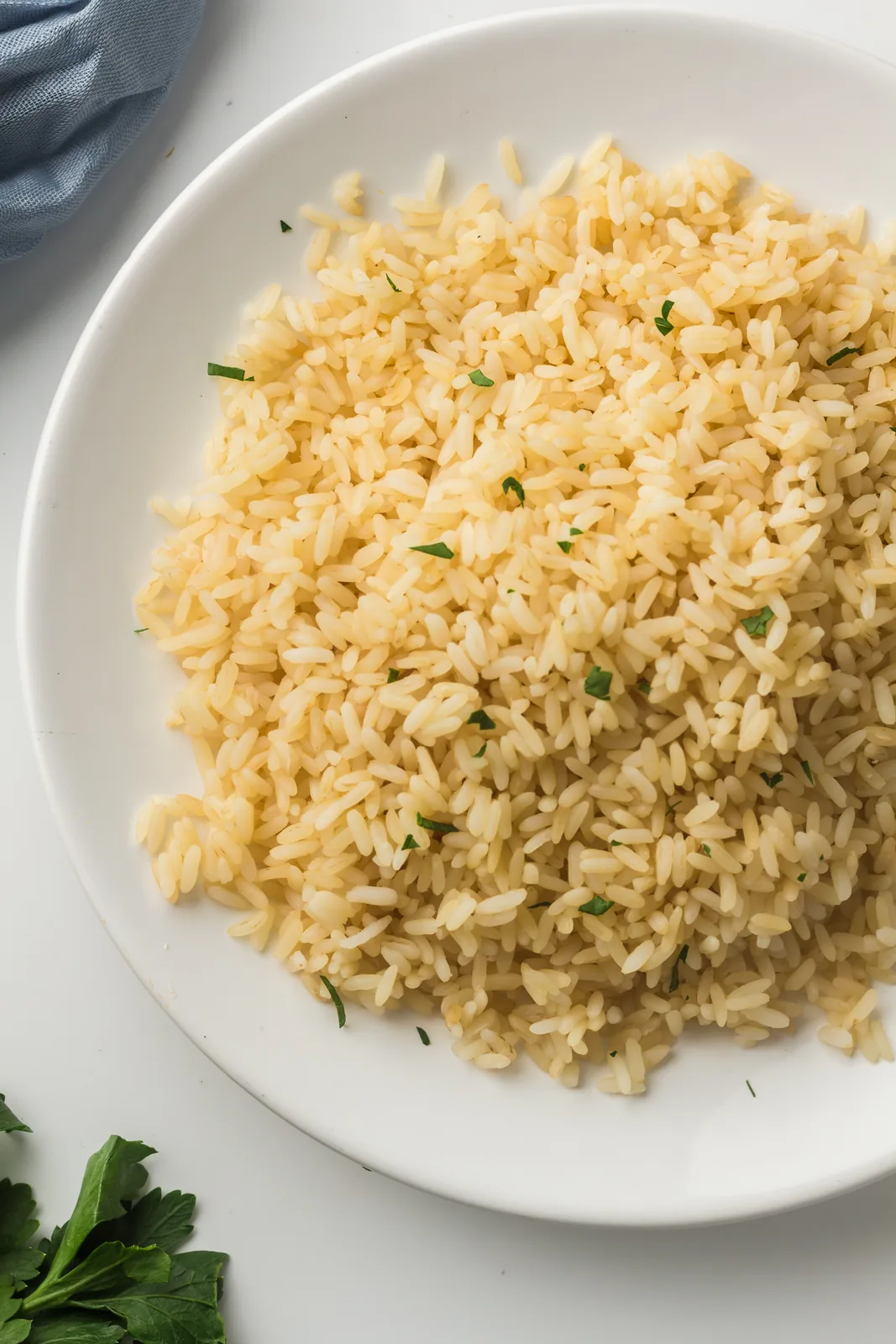 Fluffy instant pot white rice served on a white plate with chopped parsley