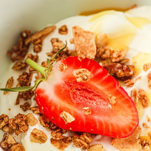 A bowl of thick instant pot yogurt topped with granola, honey and a strawberry