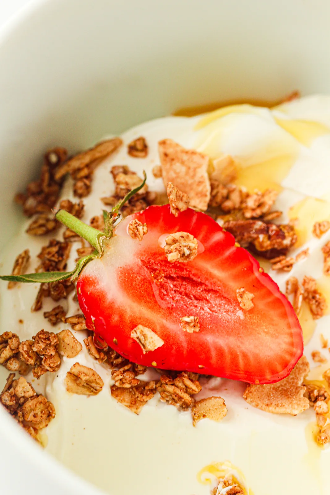 A bowl of thick instant pot yogurt topped with granola, honey and a strawberry