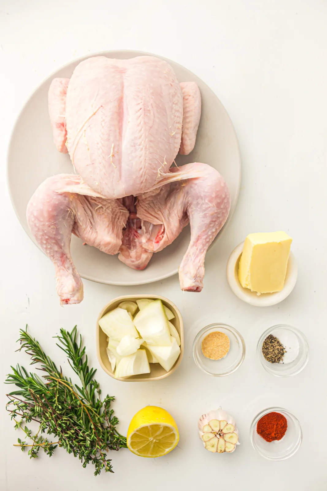 Ingredients for roast chicken: whole bird, soft butter, lemon, garlic, onion, paprika, herbs, salt and pepper