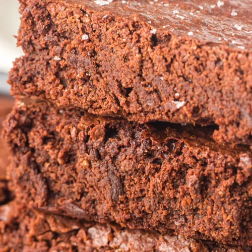 Sheet pan brownies stacked three high showing a dense fudgy interior