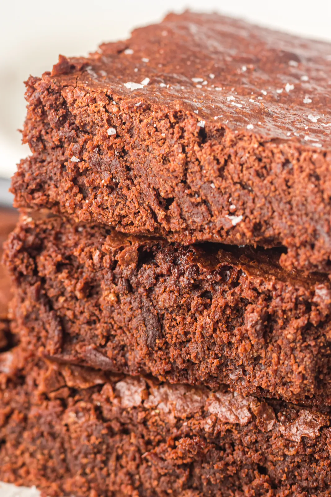 Three fudgy chocolate squares stacked showing a dense, crumb free interior