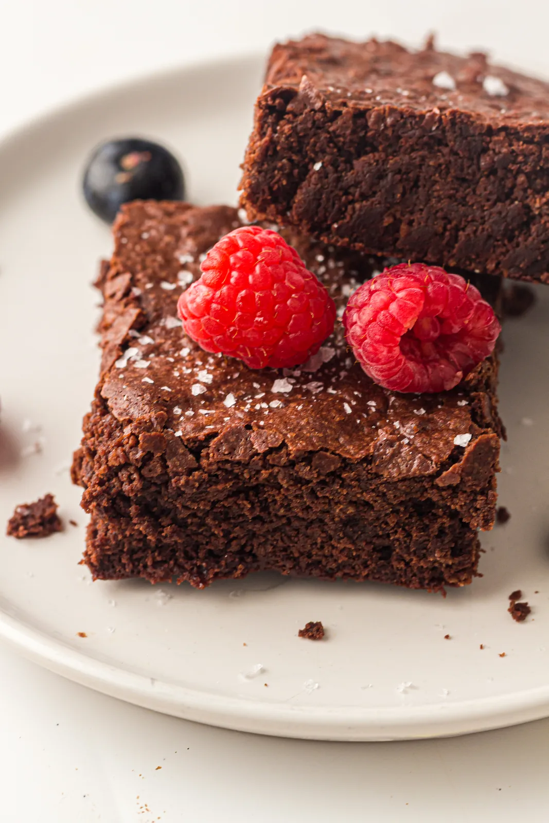 Sheet pan brownies on a small plate with fresh raspberries and a dusting of flaky salt