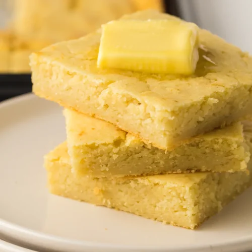 Sheet pan pancakes stacked on a plate with butter melting on top