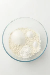 Flour, sugar and raising agents measured into a glass mixing bowl