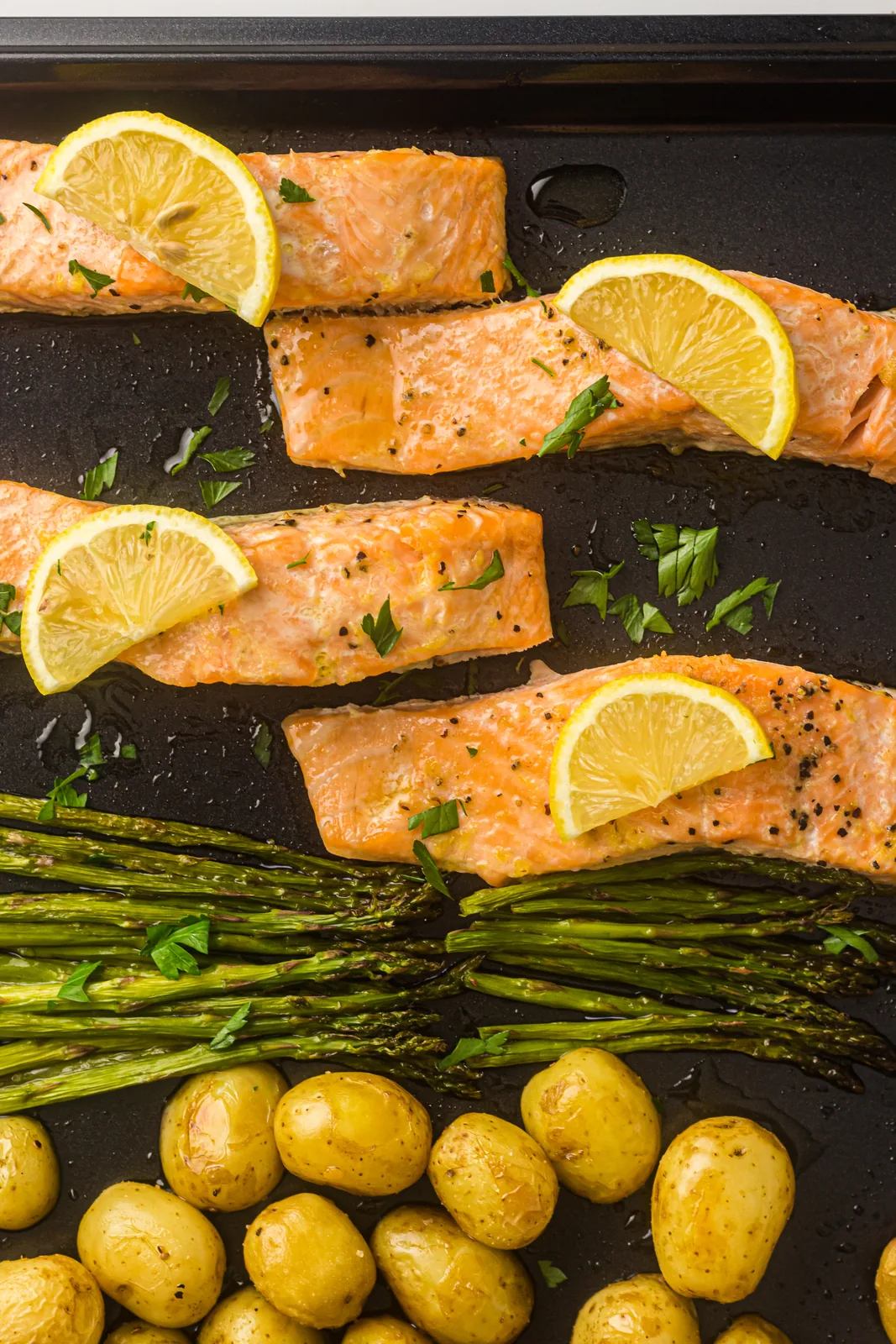 Sheet pan salmon with lemon slices, roasted potatoes and asparagus straight from the oven