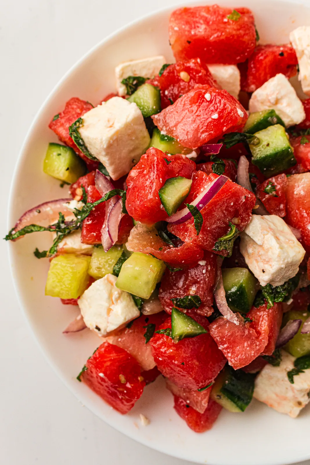 Watermelon salad with feta, cucumber and mint in a white bowl