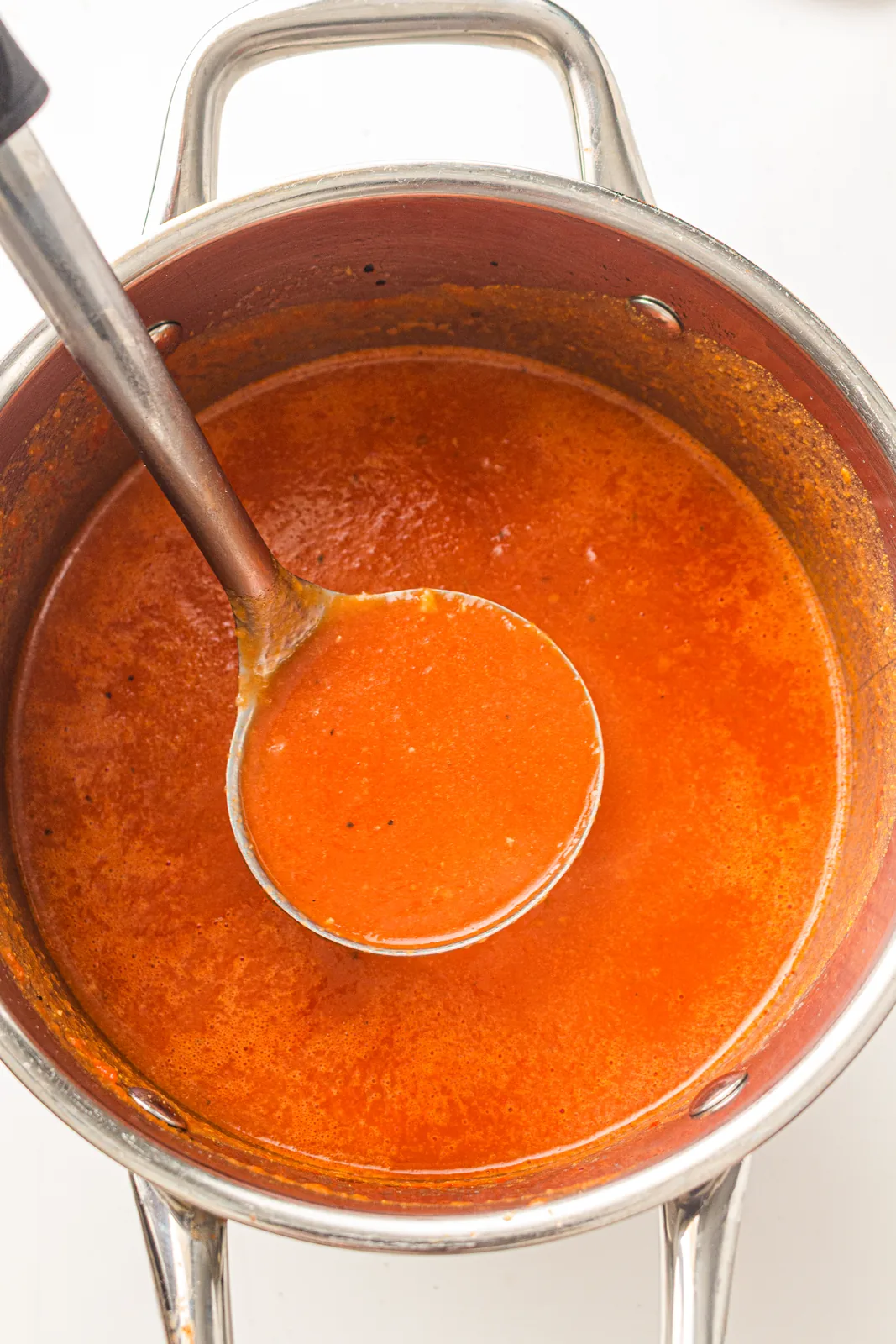 A ladle dipped into the simmering pan