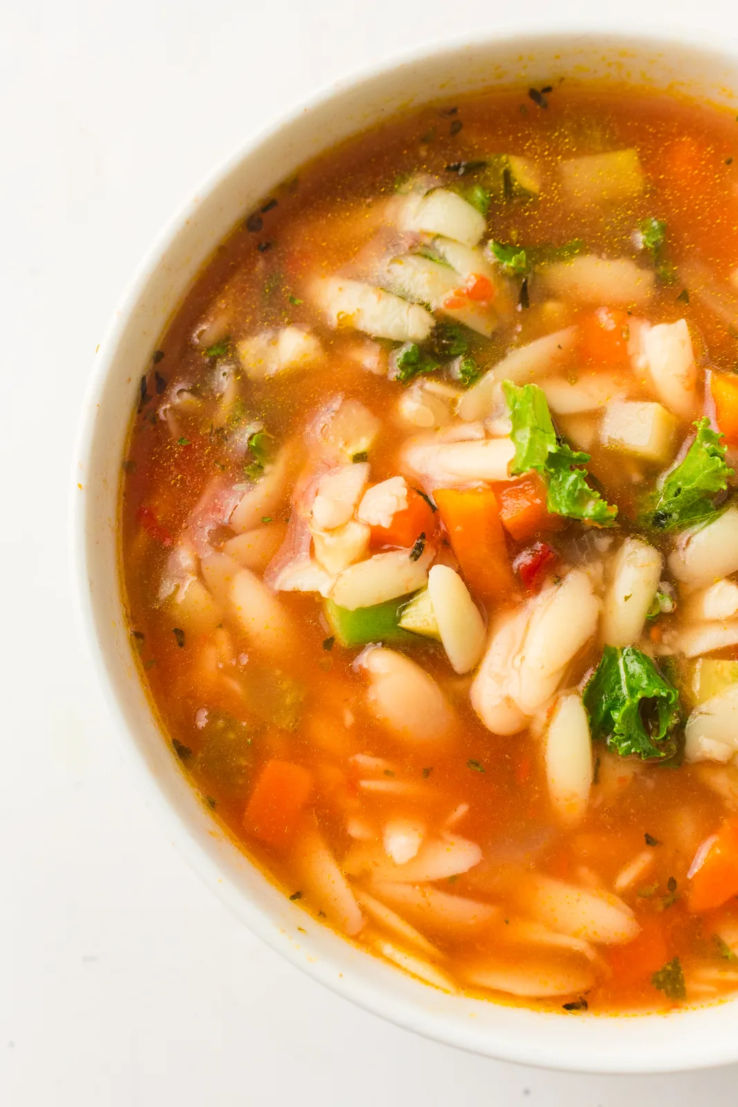 A bowl of brothy tomato broth full of diced vegetables