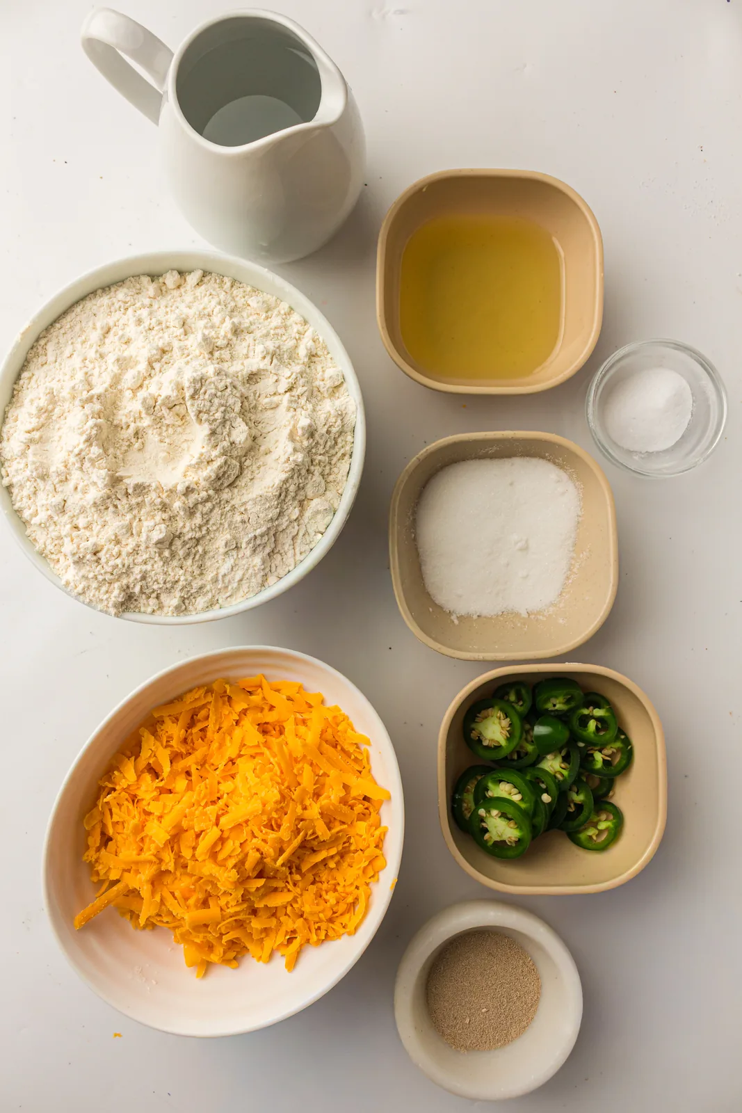 Ingredients for bread machine jalapeno cheddar bread: flour, water, oil, sugar, salt, grated cheddar, chopped green peppers and yeast