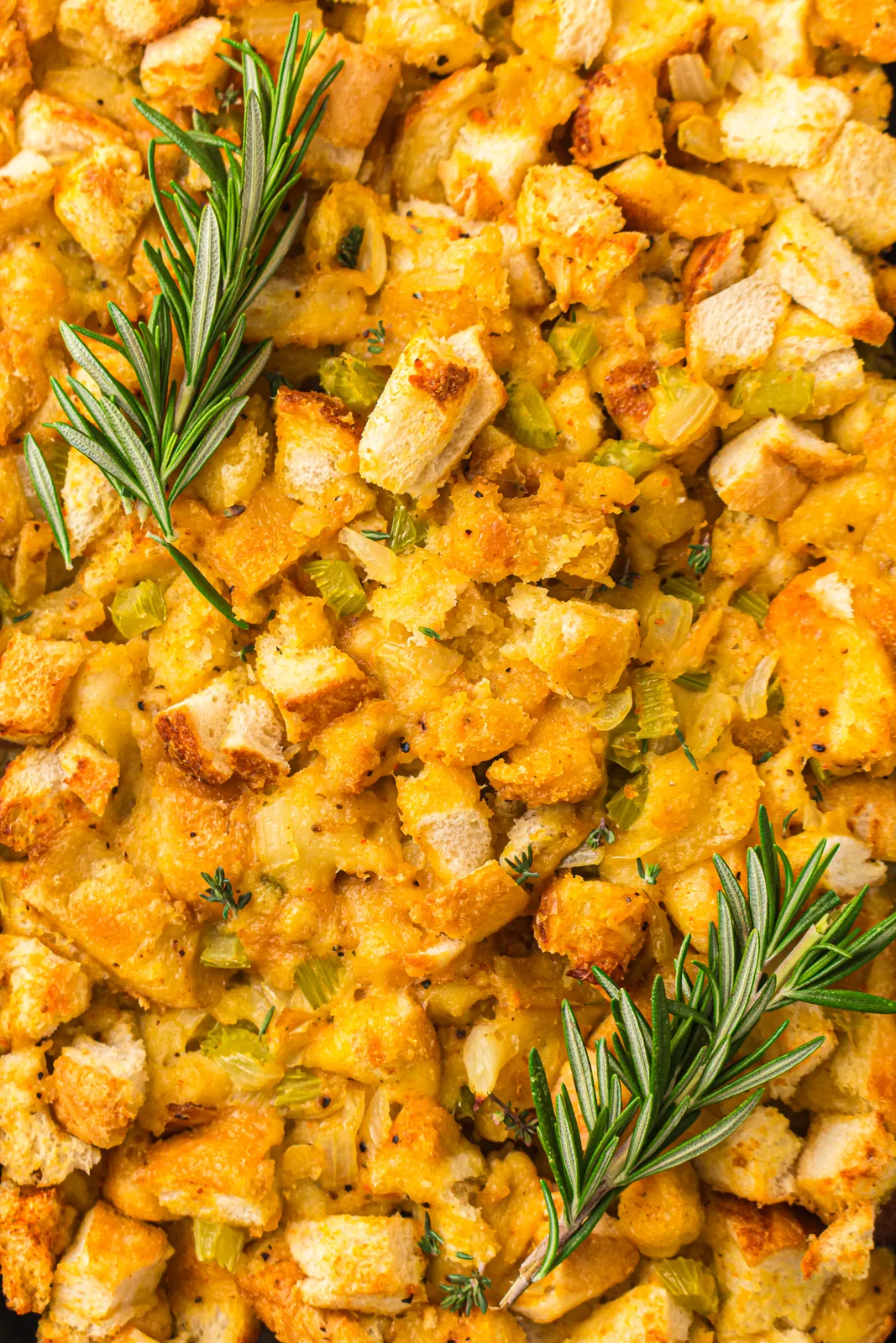 A tray of bread stuffing scattered with rosemary seen from above