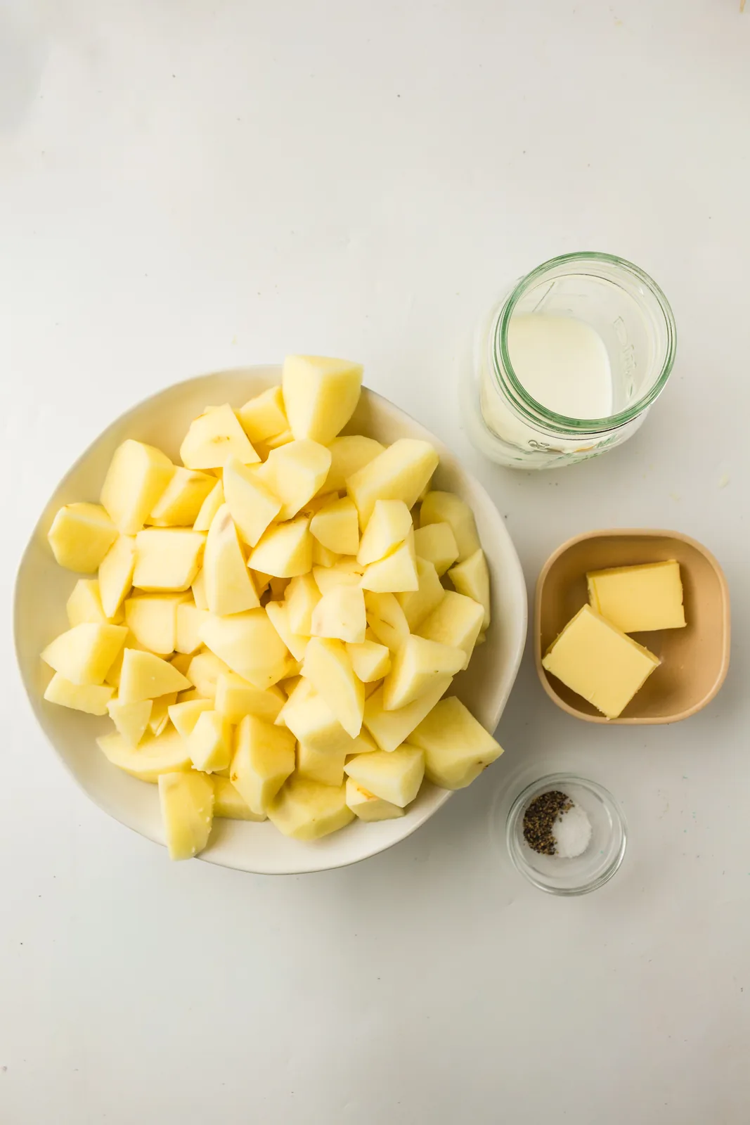 Ingredients for buttery mashed potatoes: peeled potato cubes, butter, cream and salt