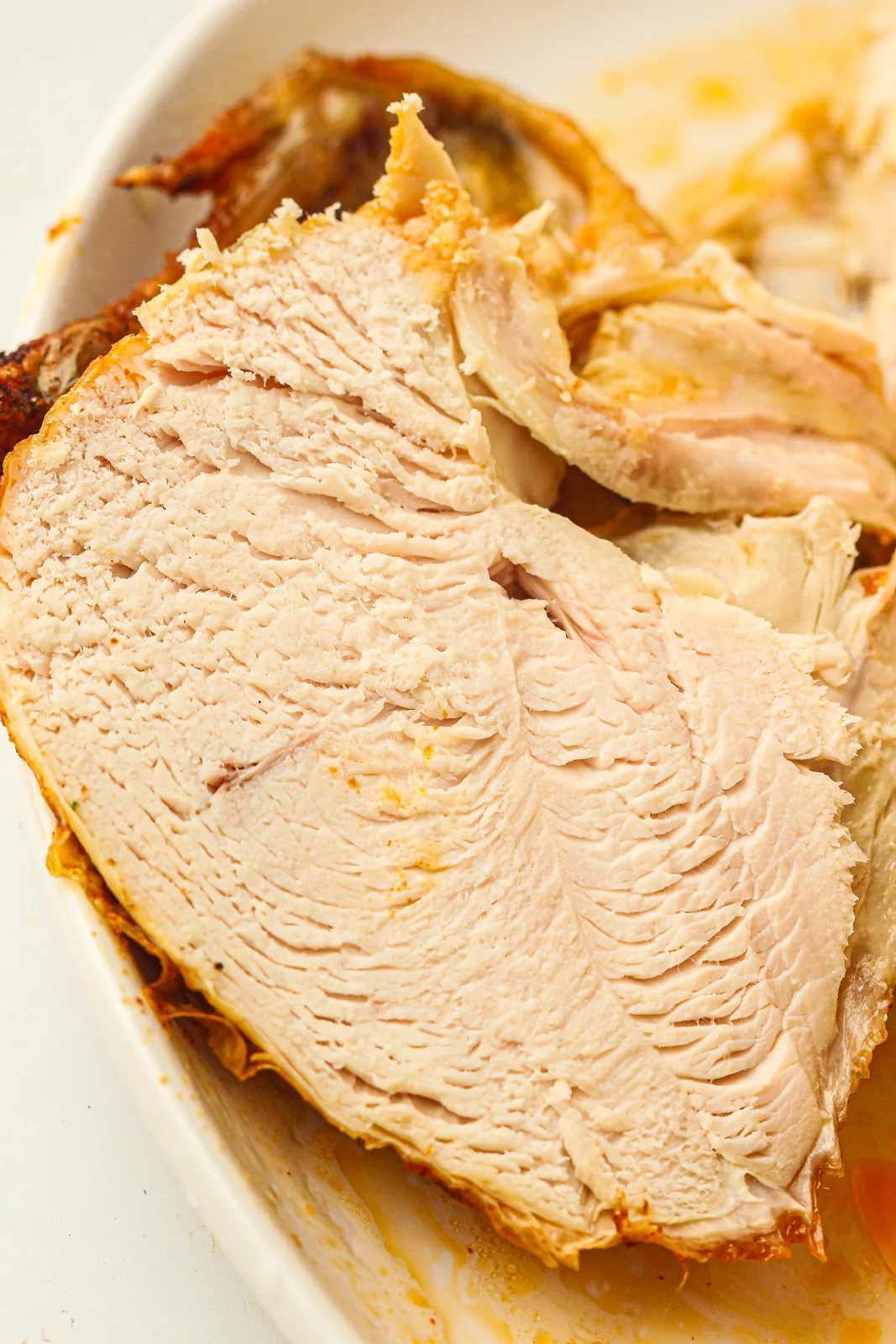 Slices carved from a slow cooker whole chicken in a serving dish