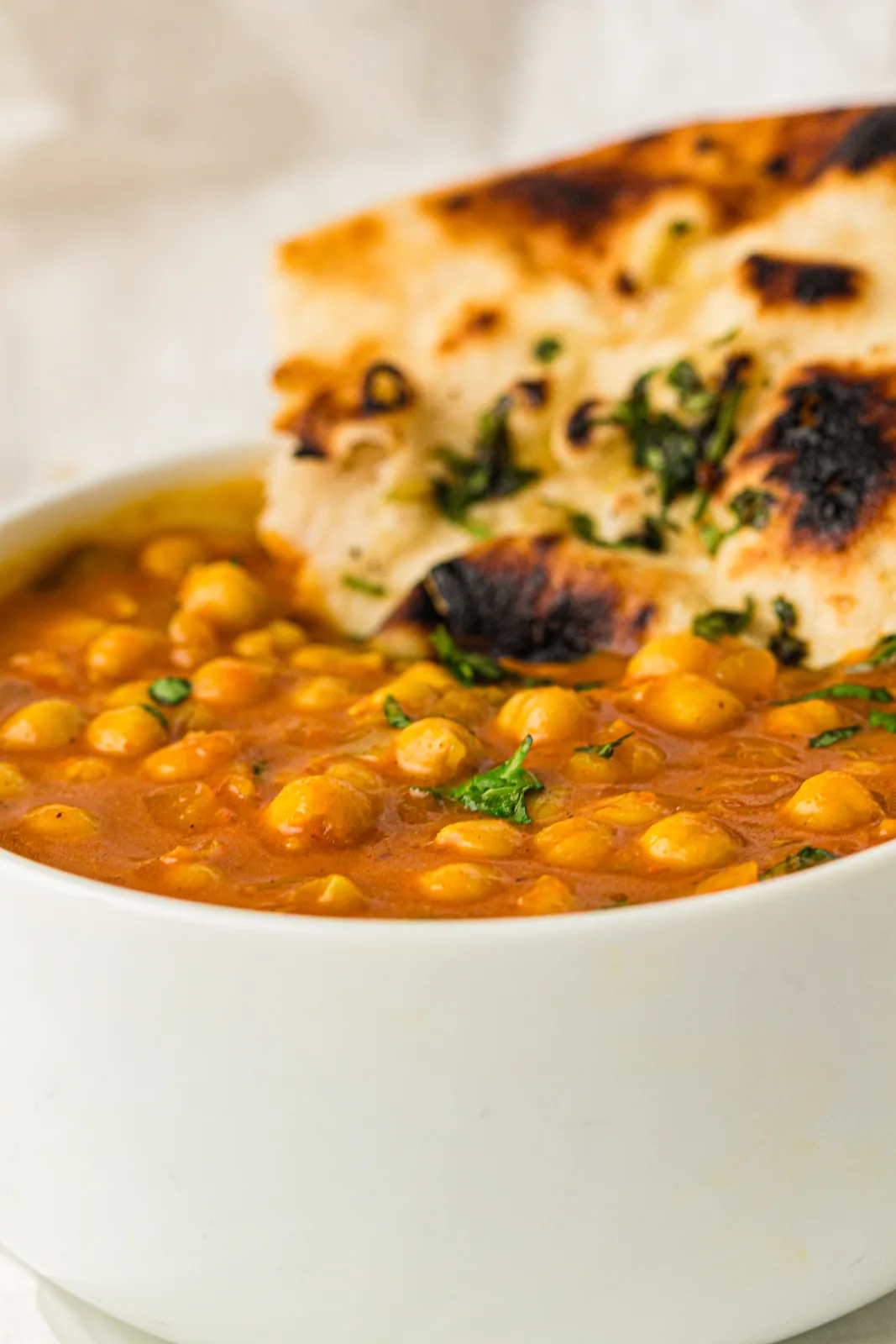 Coconut chickpea curry in a white bowl with fresh coriander