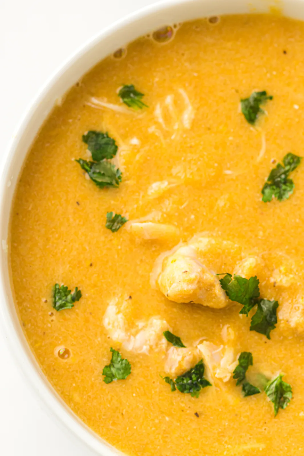 A bowl of creamy chicken vegetable soup scattered with parsley