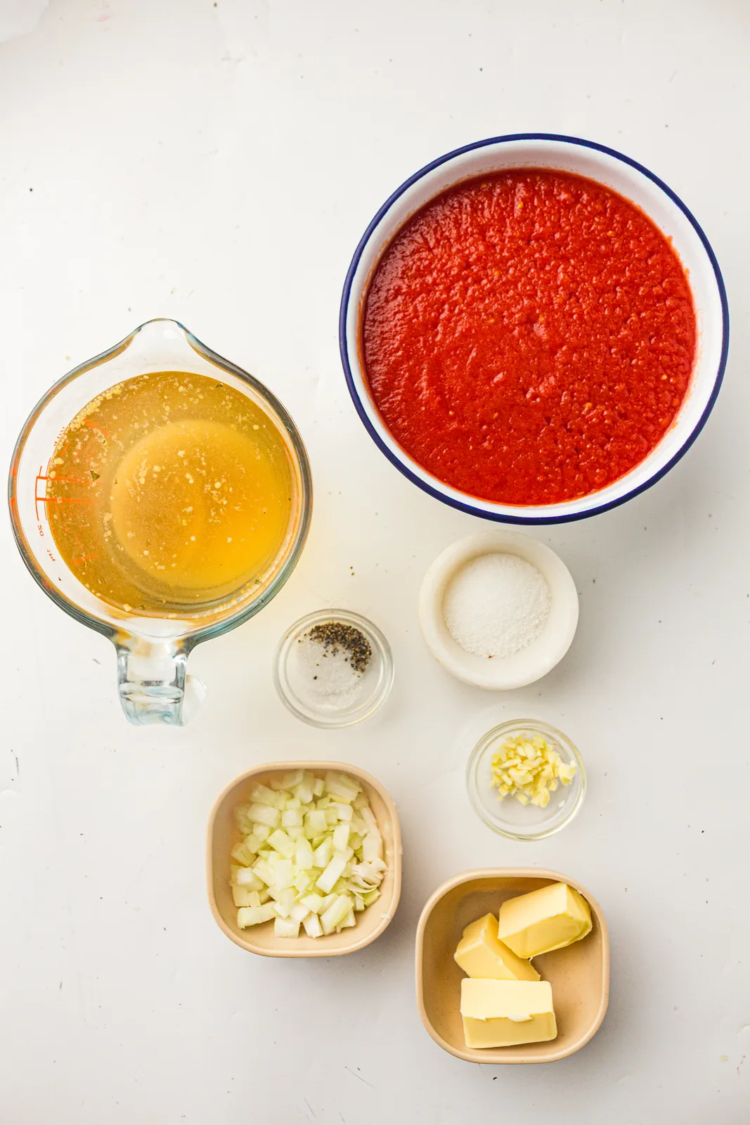 Ingredients for creamy tomato soup: tinned tomatoes, stock, butter, onion and garlic