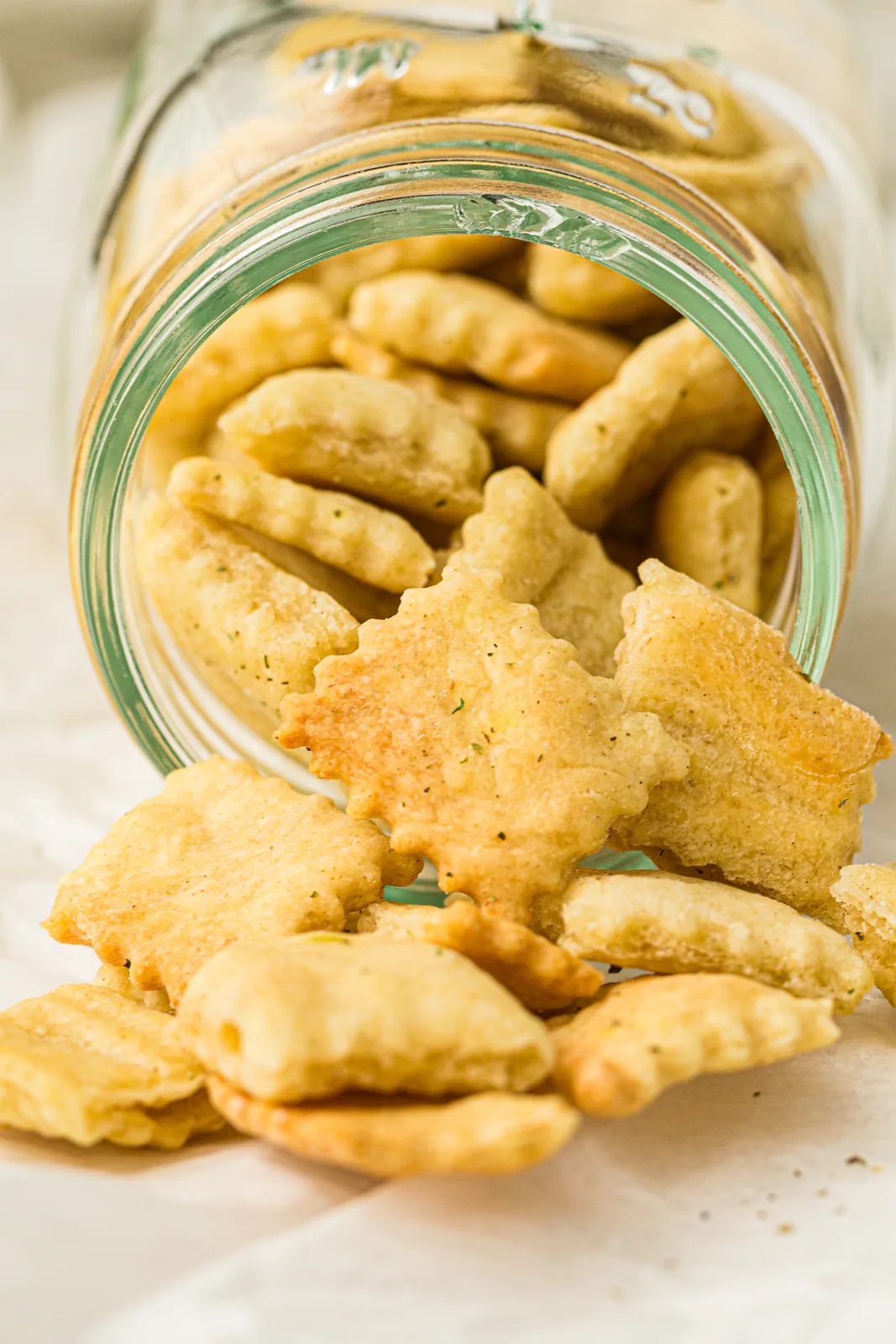 Crisp herby squares tumbling out of a tipped glass jar