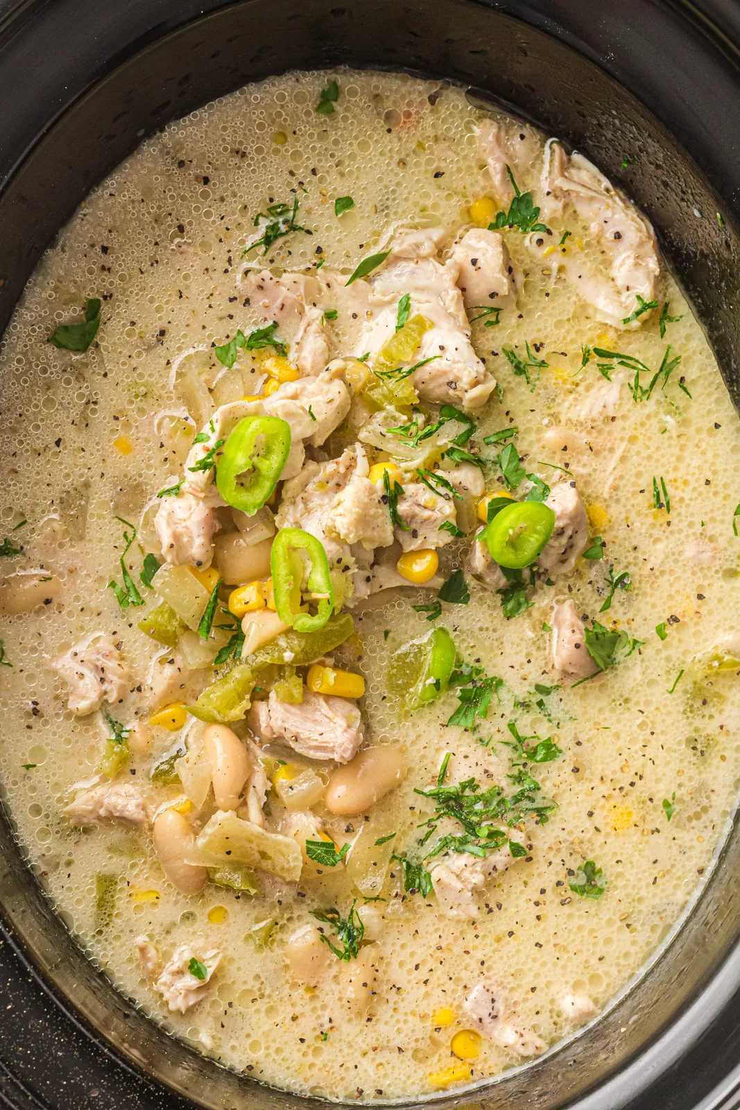 Crockpot white chicken chili in the pot with sweetcorn, white beans and coriander