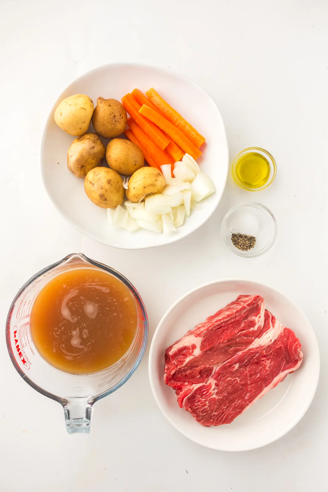 Ingredients for dutch oven pot roast: chuck roast, potatoes, carrots, onion, beef stock and olive oil
