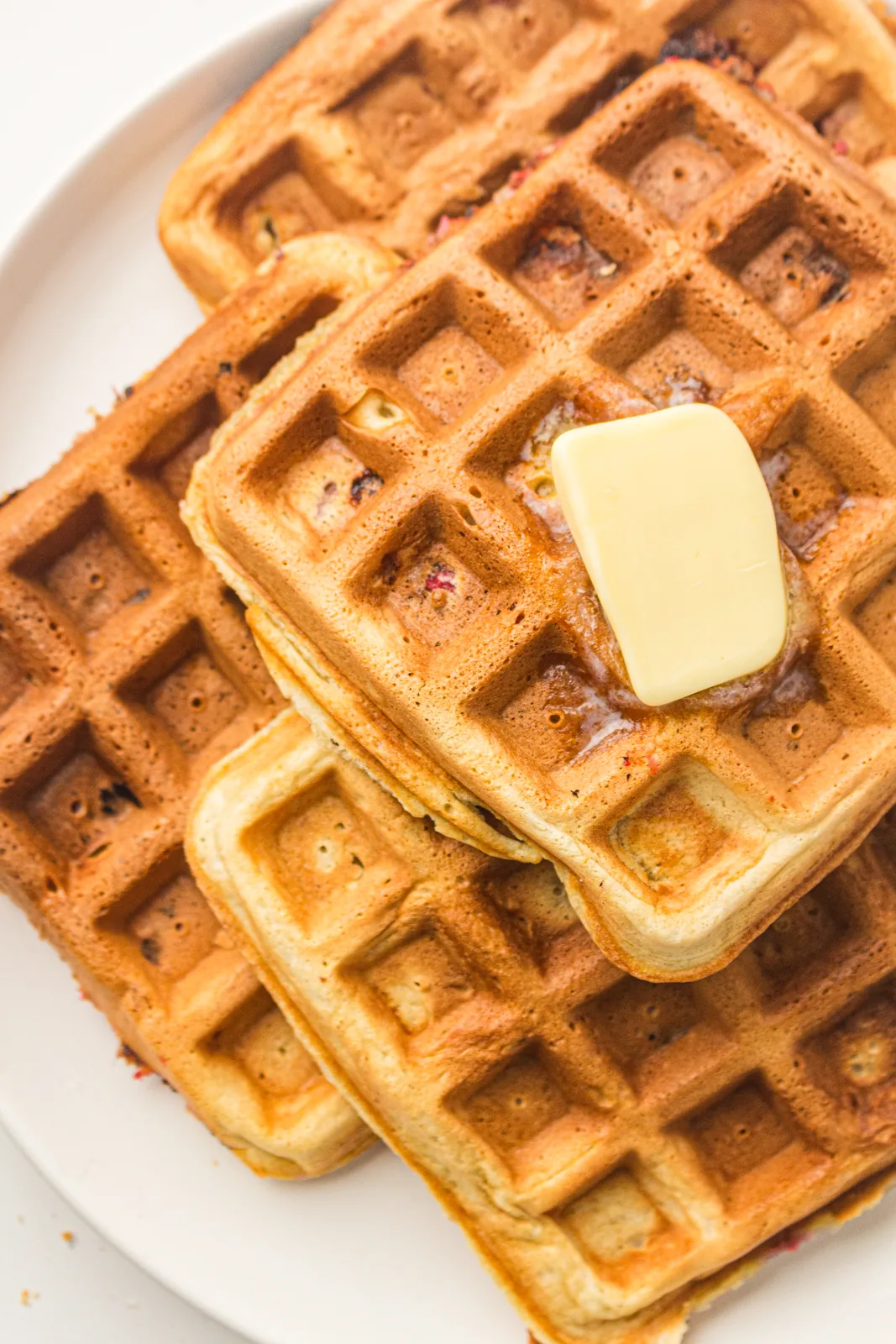 Golden squares stacked on a white plate with butter melting on top