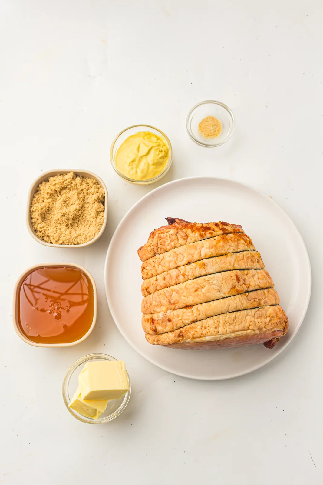 Ingredients for honey glazed ham: a scored joint, honey, brown sugar, Dijon mustard, butter and garlic powder