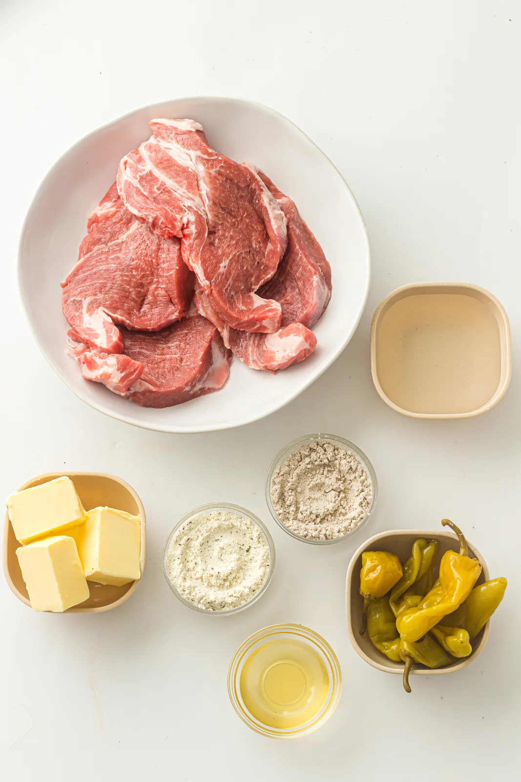 Ingredients for mississippi pork roast: pork shoulder, butter, ranch and au jus packets, pepperoncini and brine
