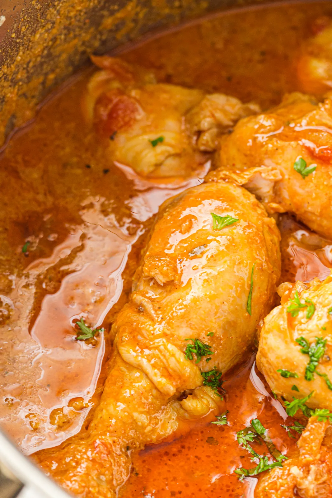 The pot of glossy orange sauce with chicken pieces nestled in it
