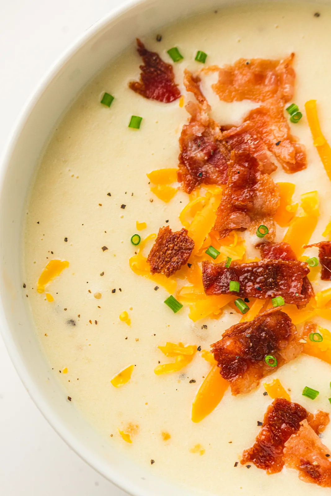 Bowl of creamy potato soup topped with crisp bacon, cheddar and chives