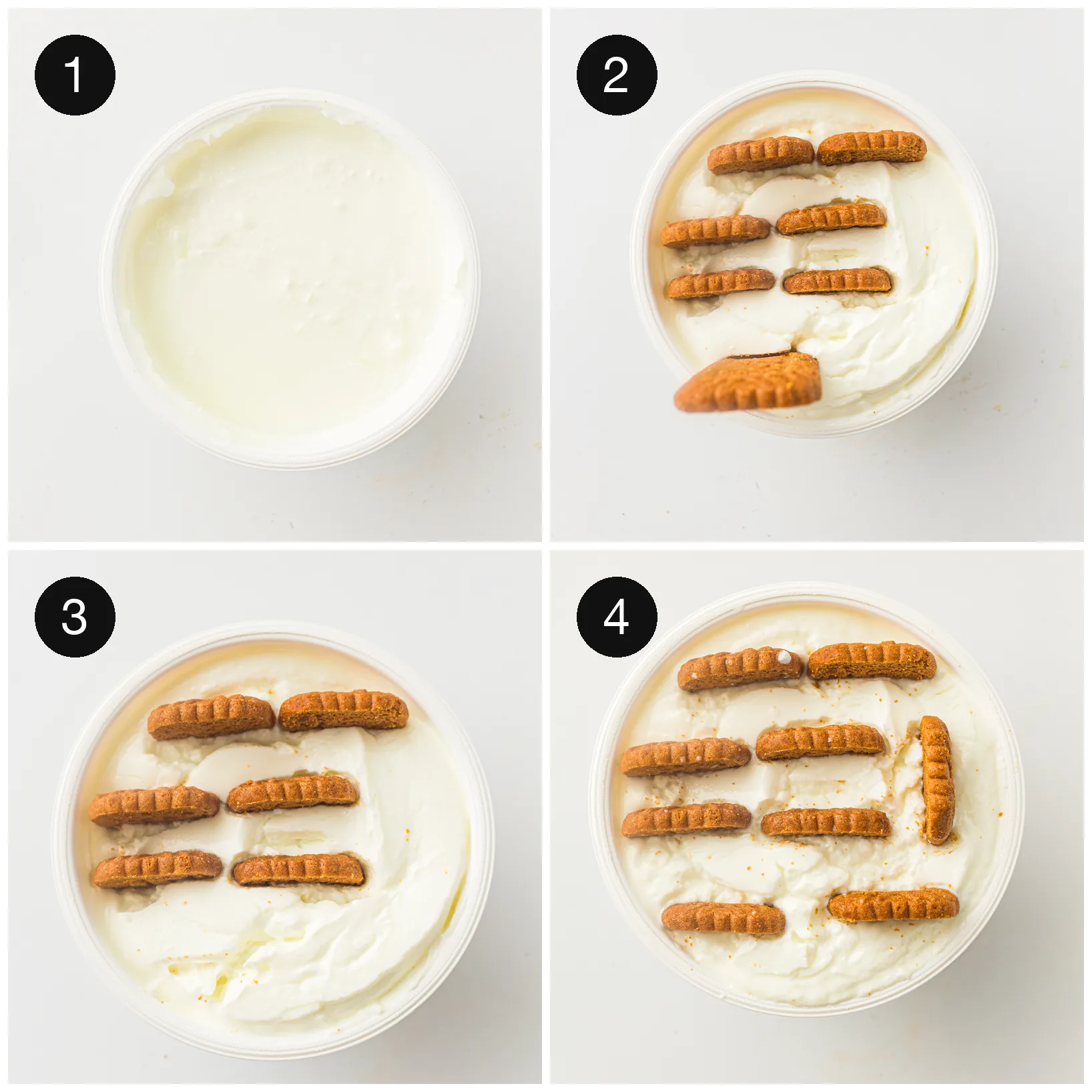 Caramel biscuits being pressed upright into a tub of thick white yogurt